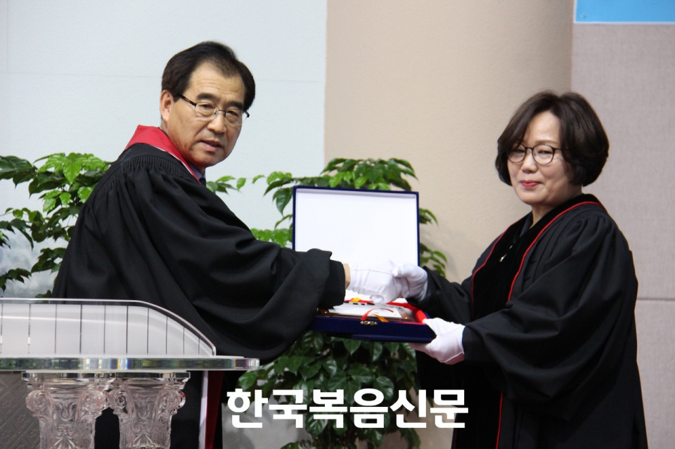안수위원장 이기봉 목사가 김성자 목사에게 임직증서 및 패를 수여하고 있다.