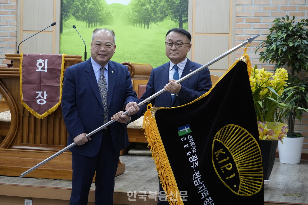 직전회장 조형국 장로(왼쪽)가 신임회장 송하정 장로에게 장로회 깃발을 전달하고 있다.